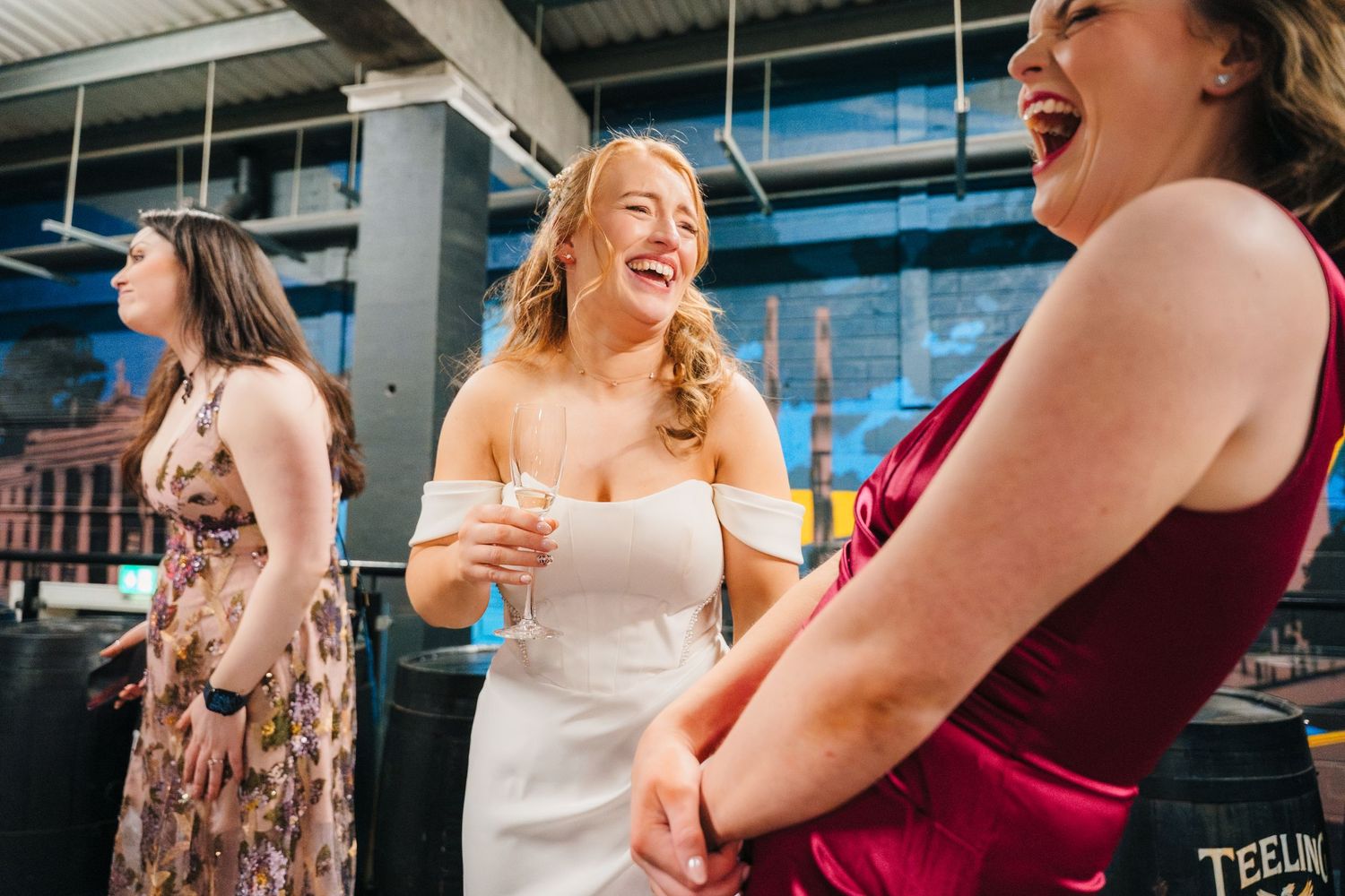 A group of people laughing and socializing at an outdoor gathering while holding drinks. Dublin wedding photogrAPher