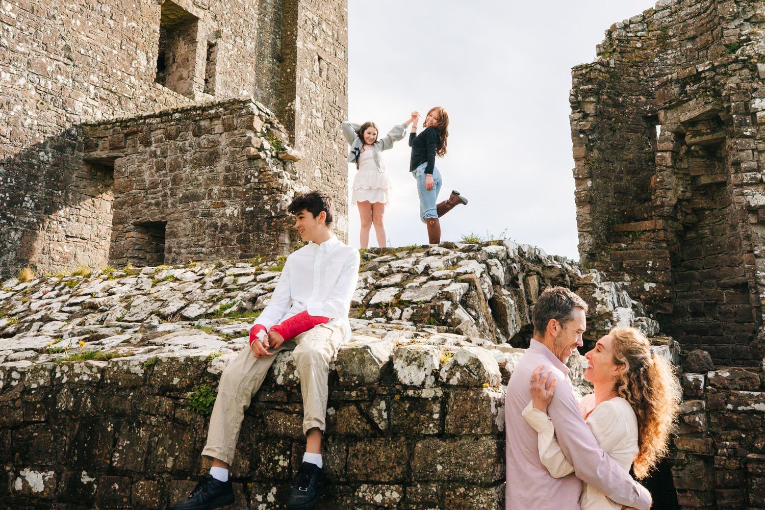A couple shares a romantic moment against ancient stone castle walls during a wedding photoshoot. Family photographer dublin
