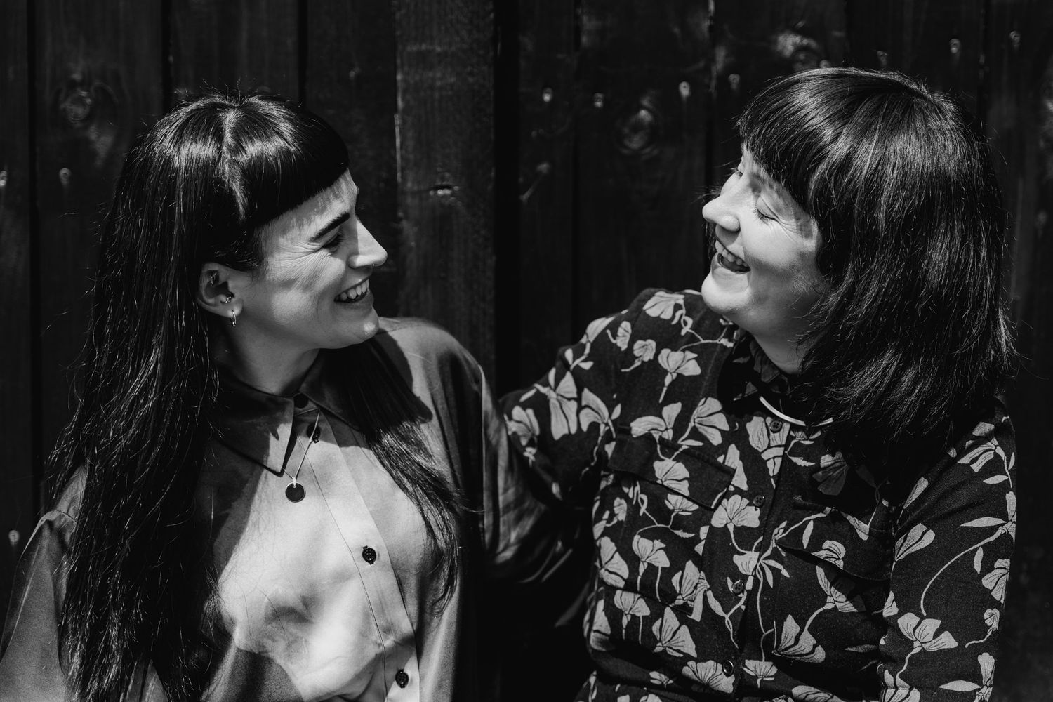 Black and white photo of two smiling people with dark hair and bangs sharing a candid moment together. PHOTOGRAPHER Dublin ireland