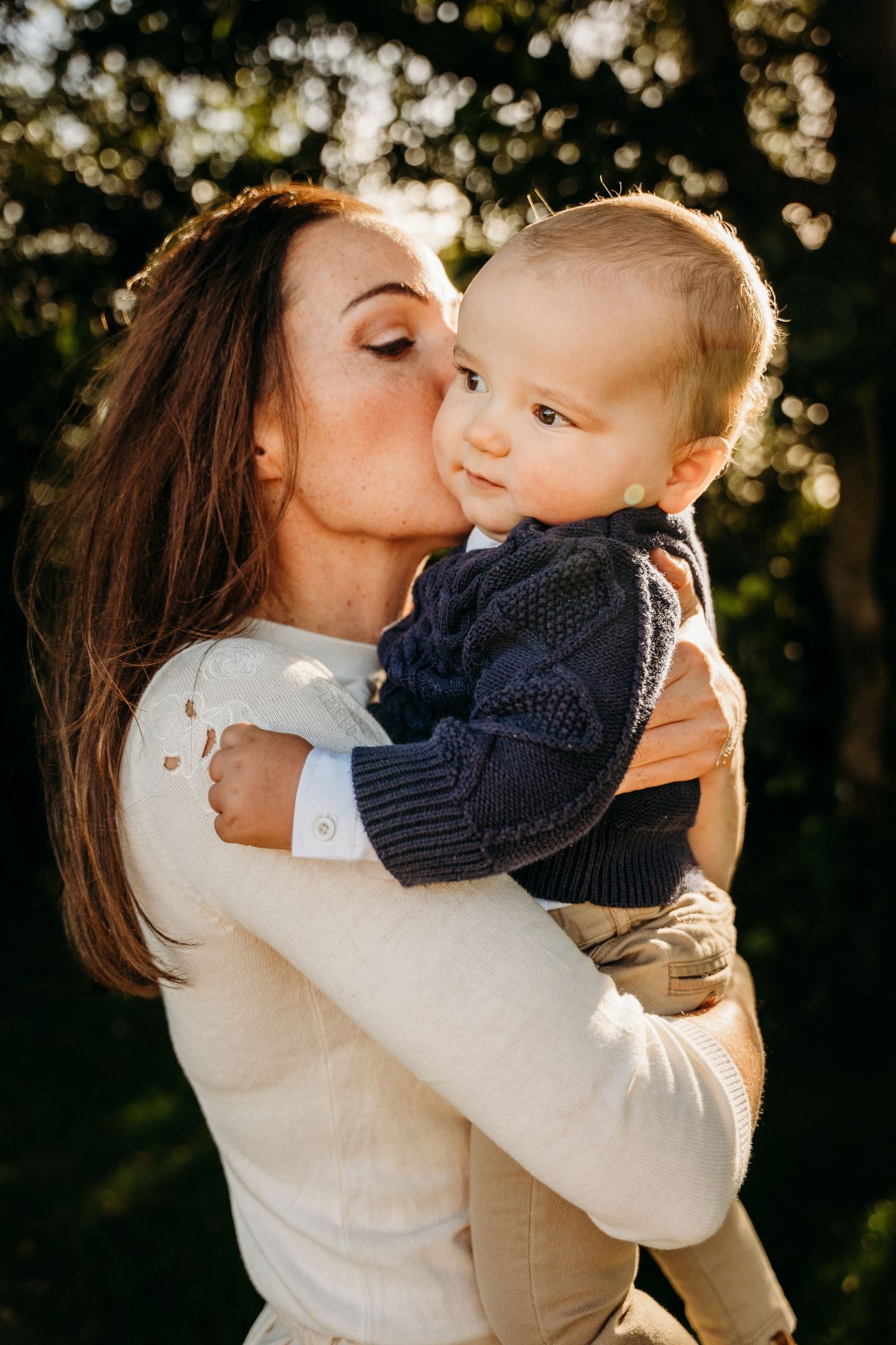 Sweet outdoor portrait showing a tender moment between parent and baby backlit by golden sunlight. family PHOTOGRAPHER Dublin