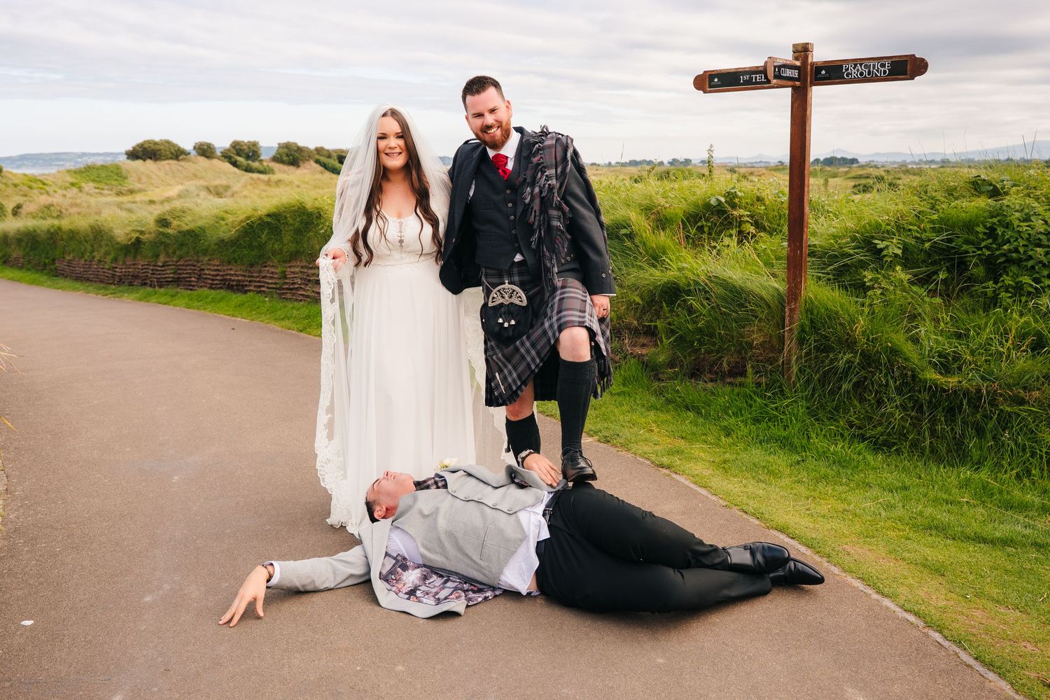 Wedding couple poses for photos on a scenic coastal pathway. Portmarnock Hotel Wedding PHOTOGRAPHER Dublin