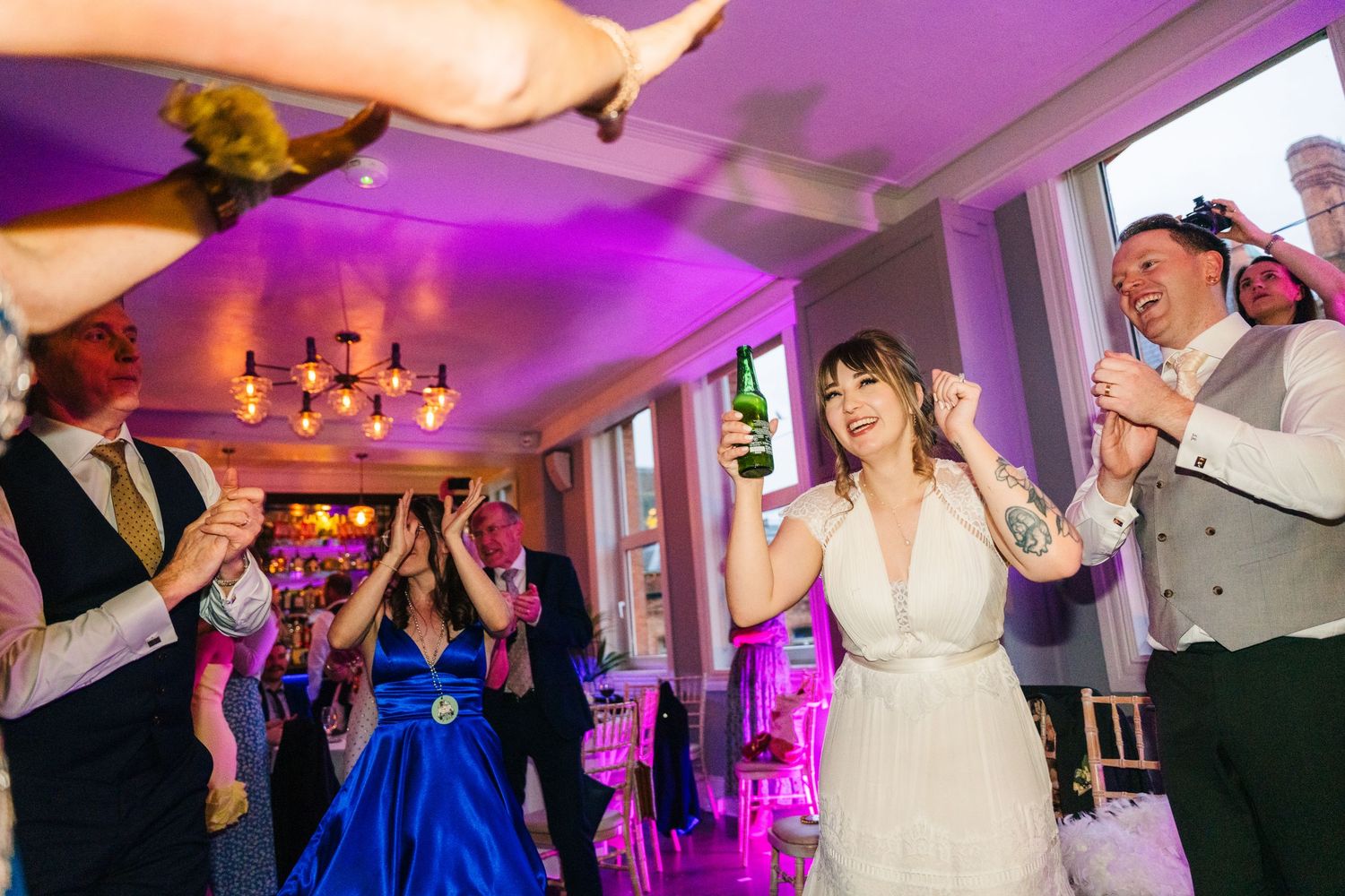 Wedding reception party with guests dancing and celebrating under purple mood lighting. PHOTOGRAPHER Dublin Ireland Wedding