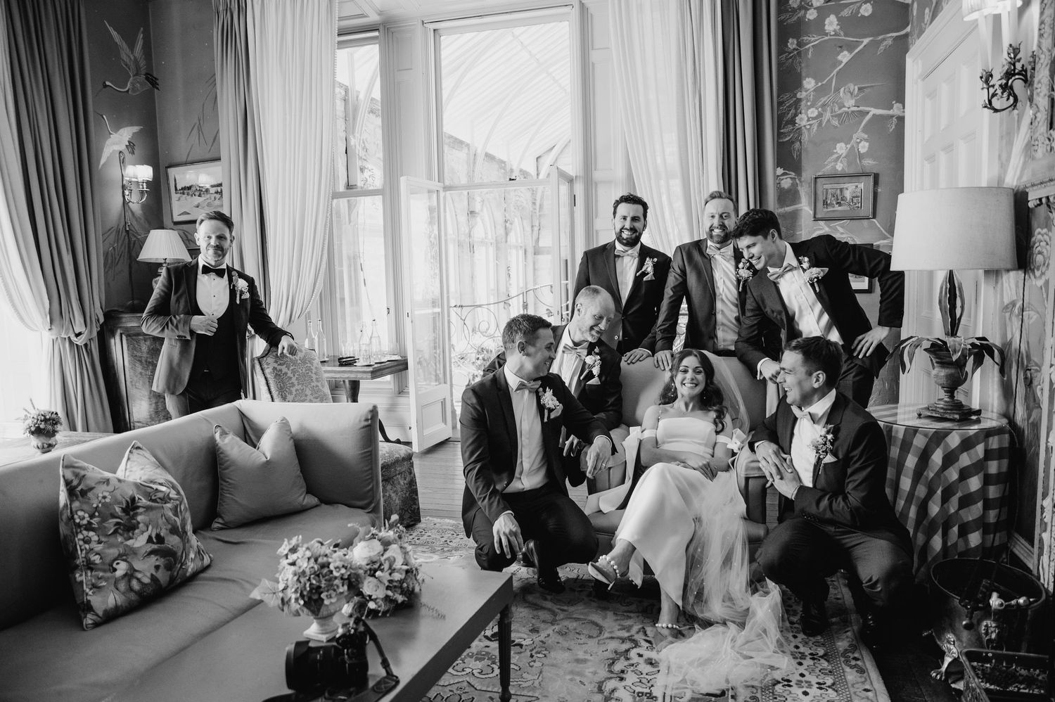 Wedding party relaxes together in elegant living room with natural light in black and white photography. Castle Leslie Wedding Photographer