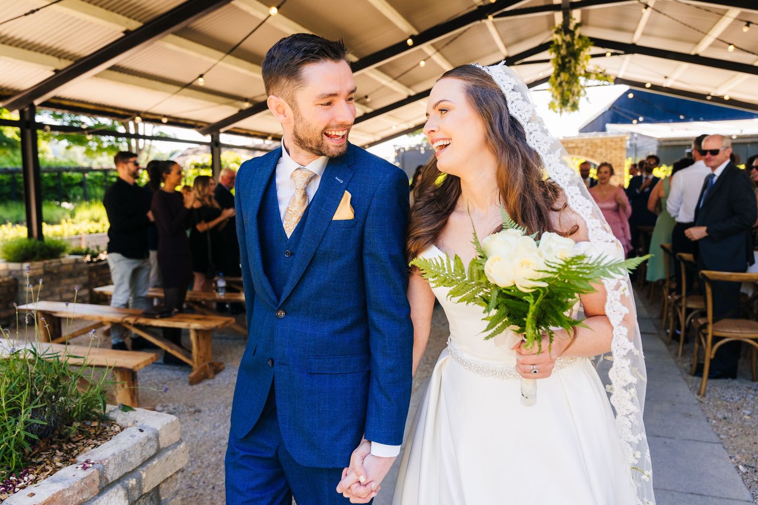 Poulaphouca Wedding photographer wicklow  A couple shares a happy moment at their outdoor wedding celebration under a covered patio.