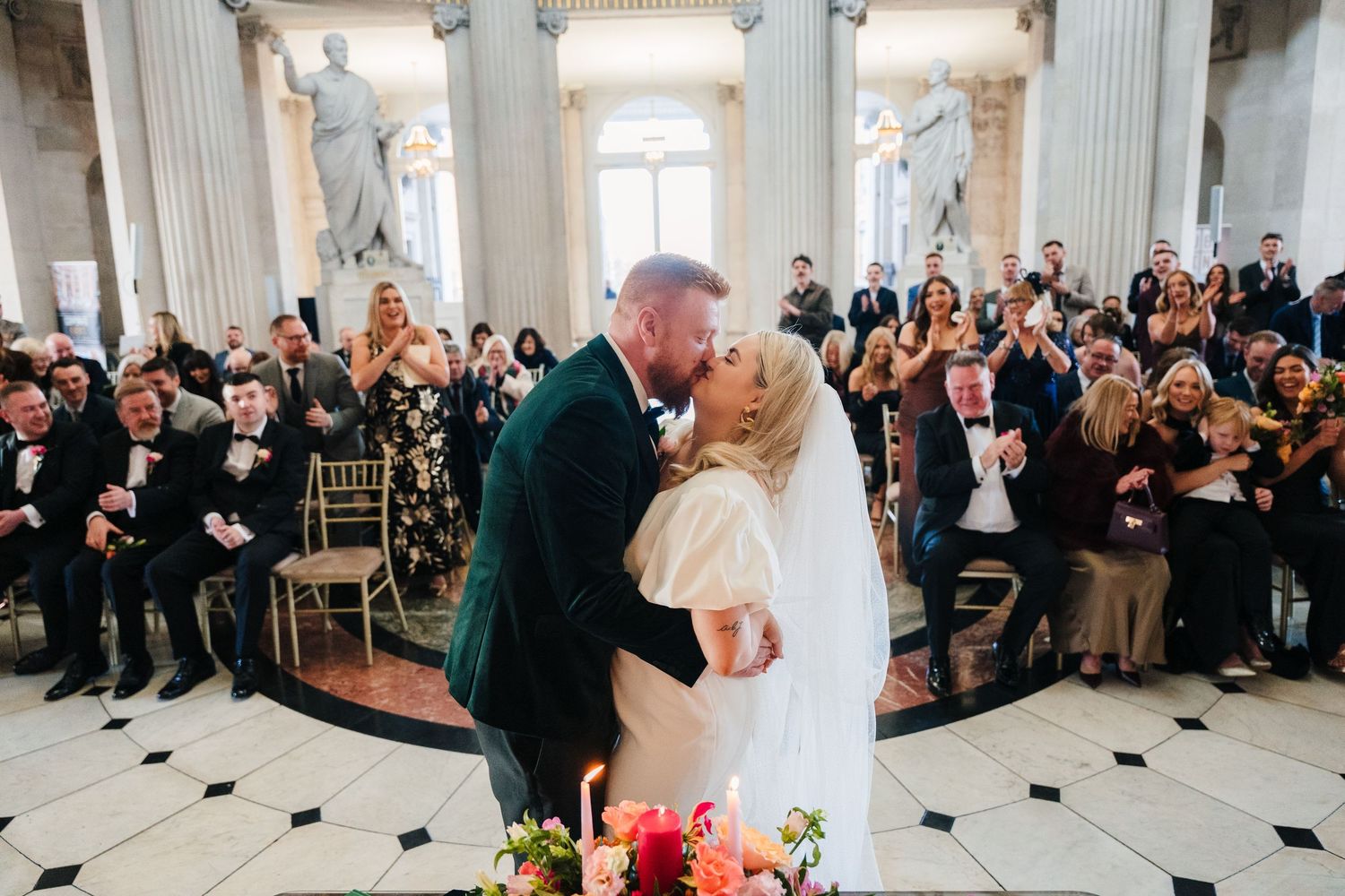 Wedding ceremony takes place in an elegant room with white columns and guests seated in rows. City Hall Dublin Photographer