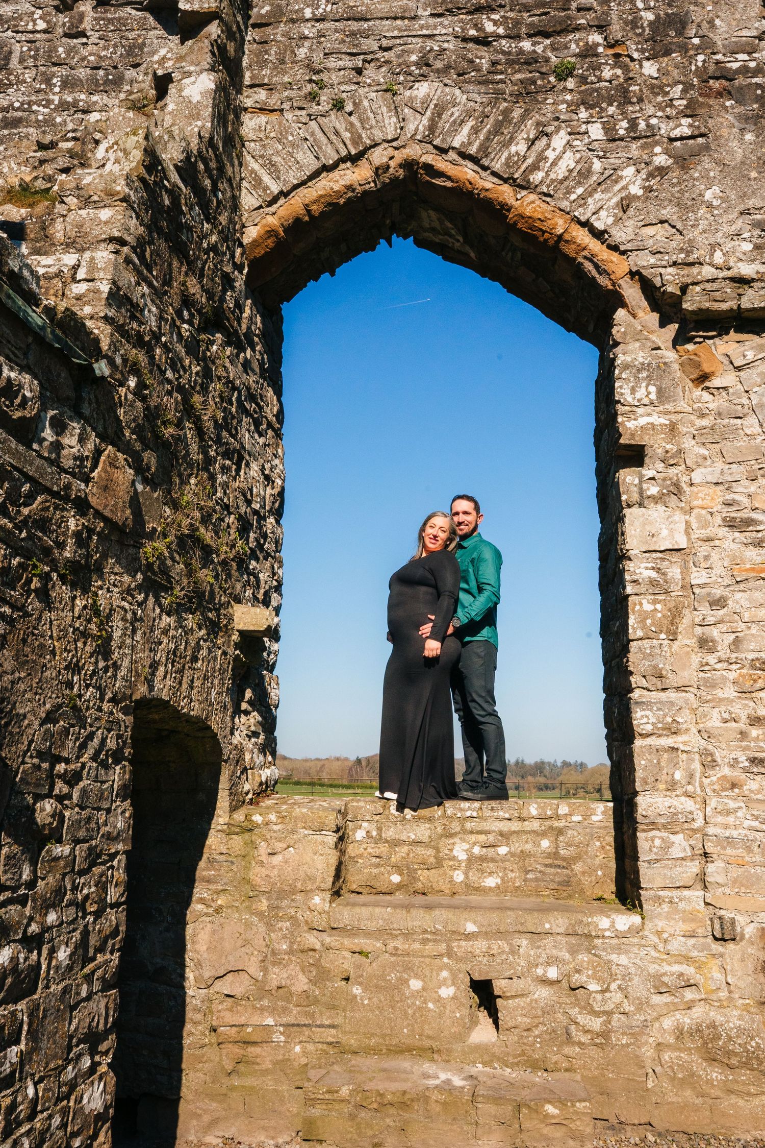 A series of photos showing figures in an ancient stone archway window against a blue sky backdrop. Family PHOTOGRAPHER Dublin