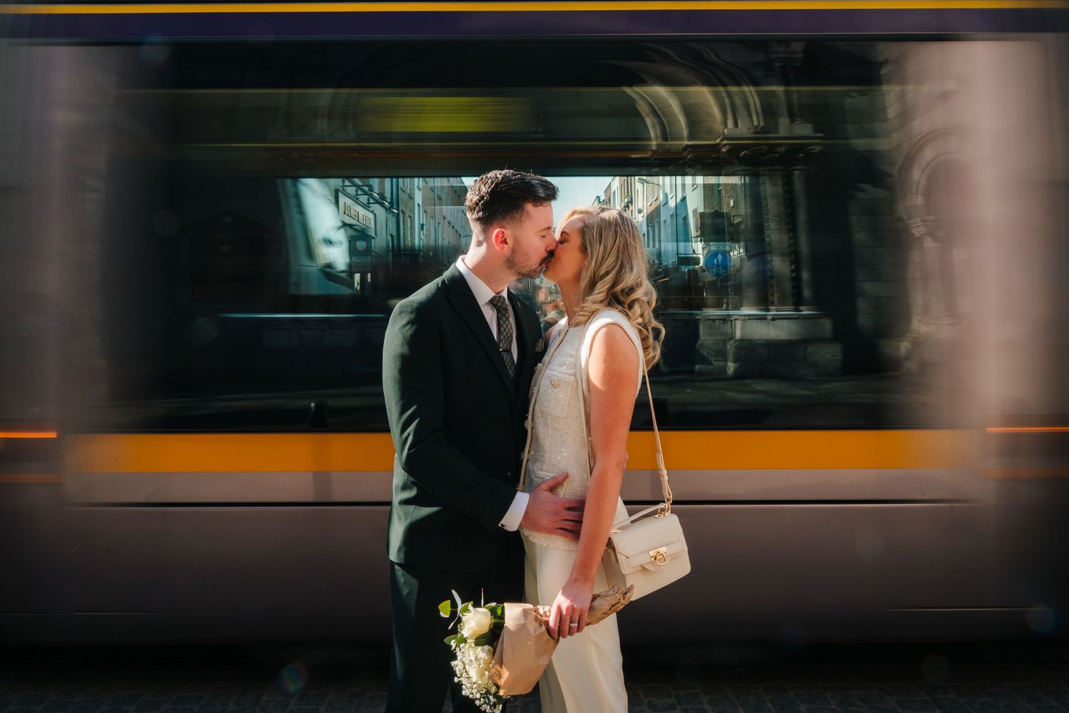Romantic wedding couple embracing in front of passing subway train with motion blur effect. City Hall Dublin wedding photogrAPher