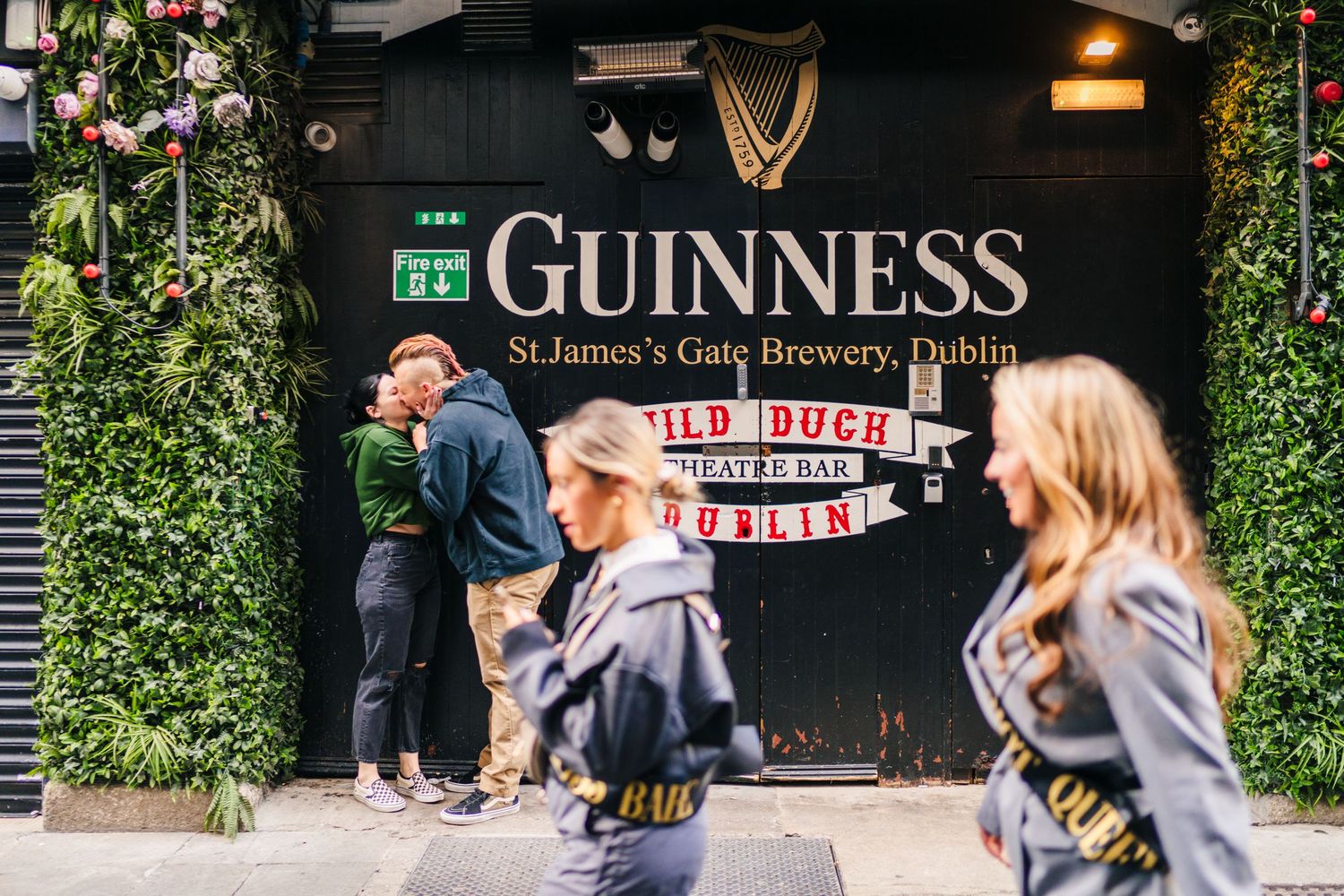 Exterior of Guinness Brewery and Wild Duck Theatre Bar in Dublin with people walking past green foliage decor. PHOTOGRAPHER Dublin Ireland