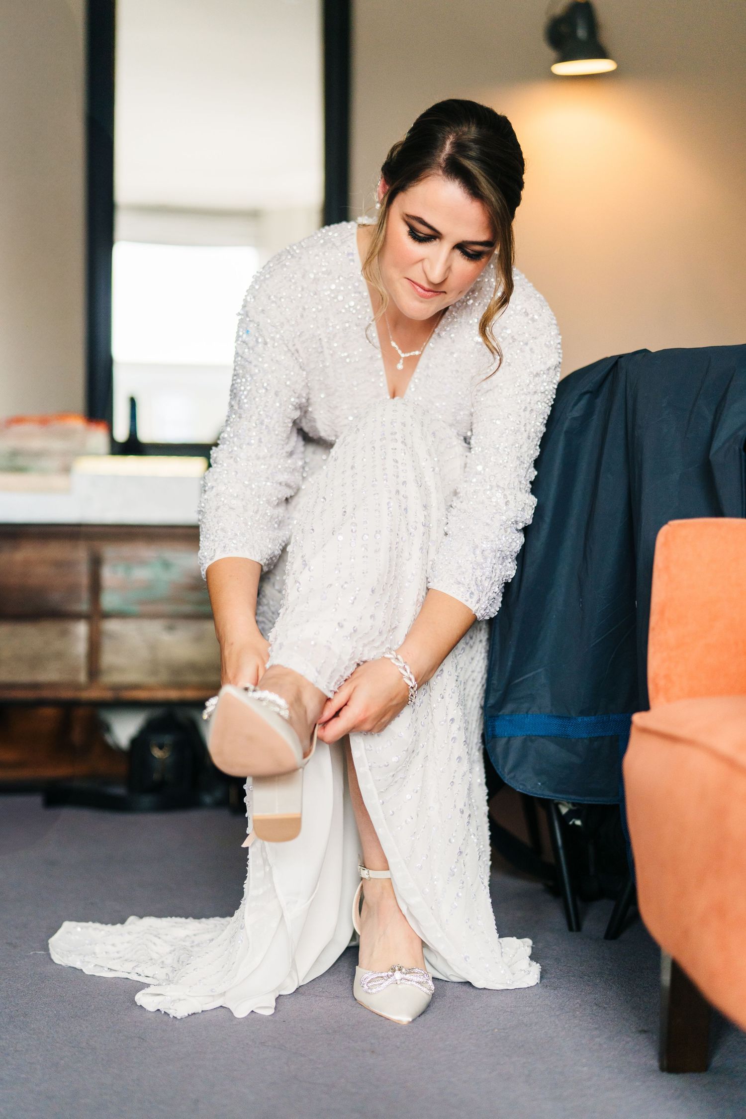 Close-up view of someone putting on white bridal shoes while wearing a delicate lace wedding dress. House Dublin Wedding Photographer