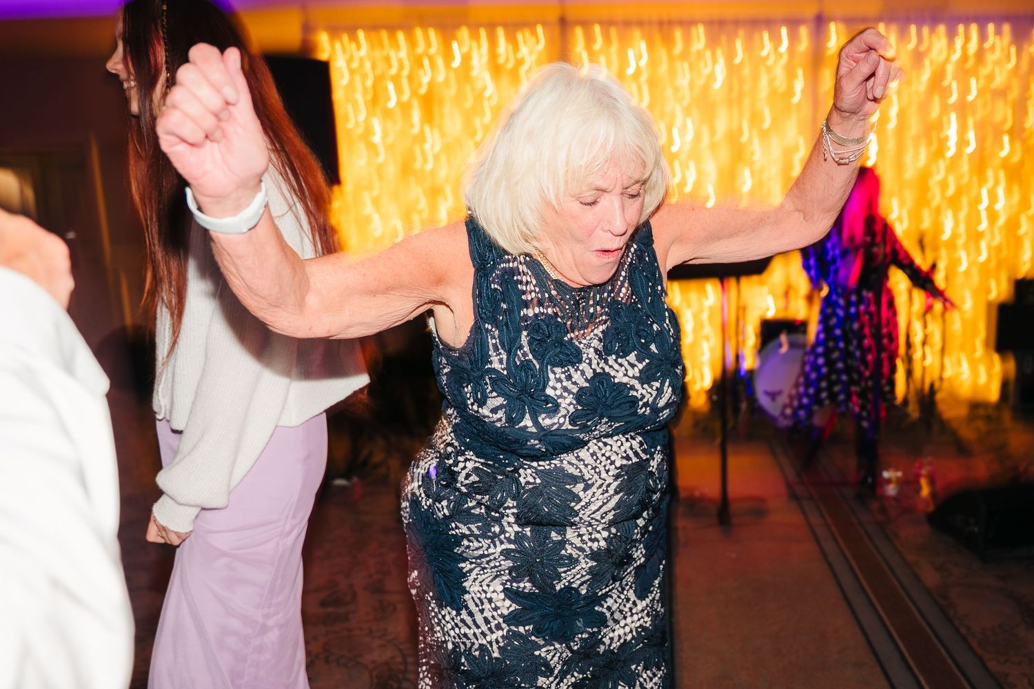 Wedding guests dance and celebrate together on a dance floor illuminated by warm glowing lights. Wedding Photographer Dublin