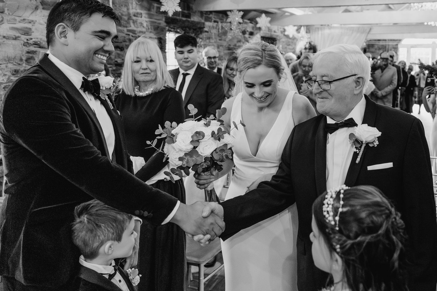 Black and white photo sequence showing joyful moments from a wedding celebration with guests and couple interacting. Ballymagarvey Wedding p
