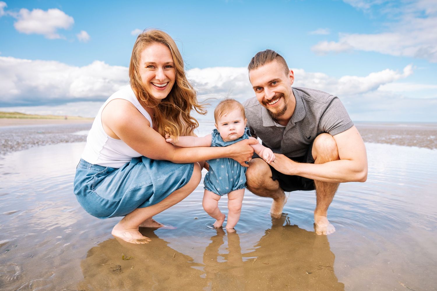 A group plays together at the beach during a sunny day while wearing denim and white clothing. Family PHOTOGRAPHER Dublin family PHOTOGRAPHE