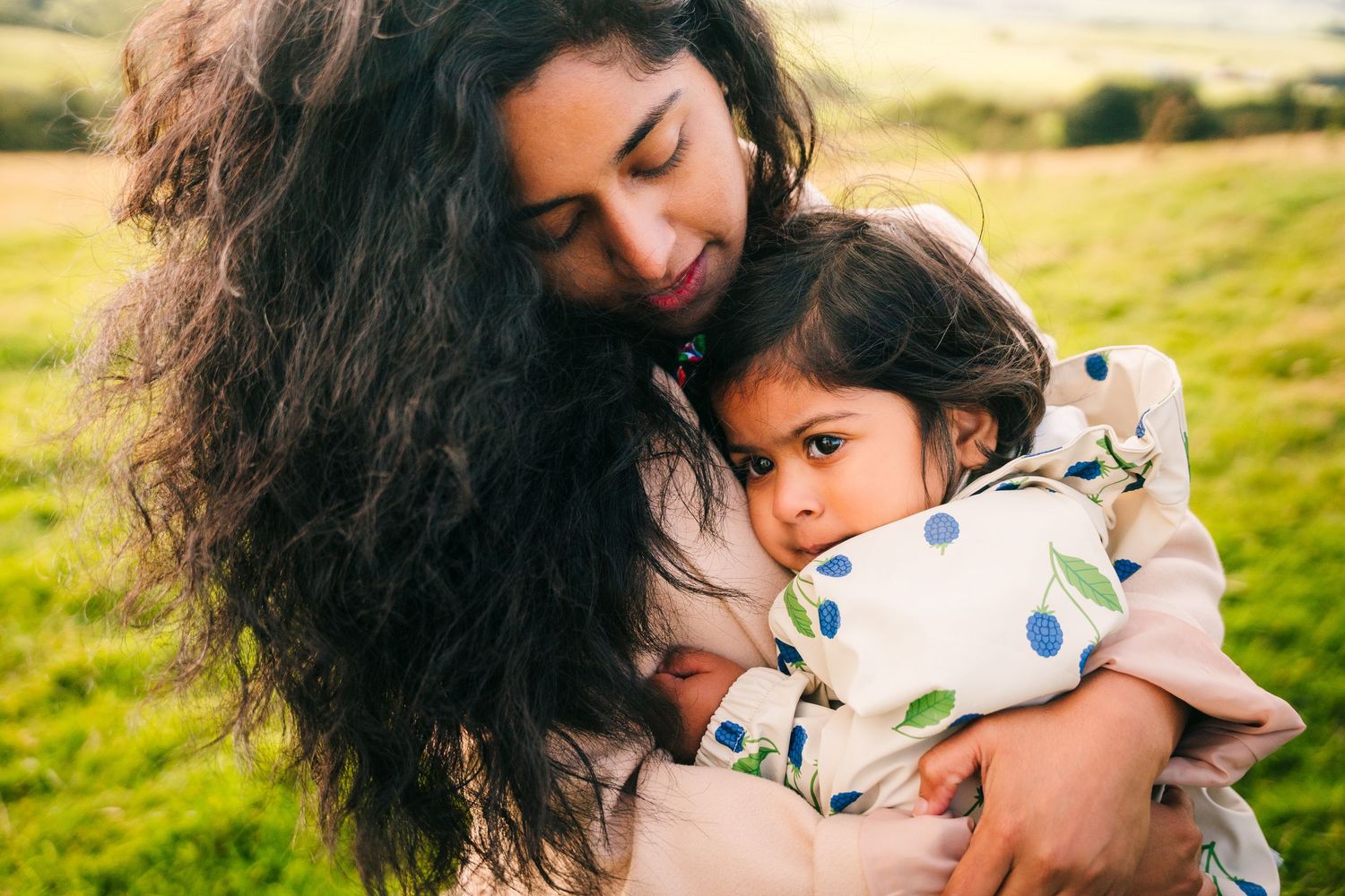 A tender embrace between parent and child in a sunny outdoor setting with a warm, natural glow. family PHOTOGRAPHER Dublin