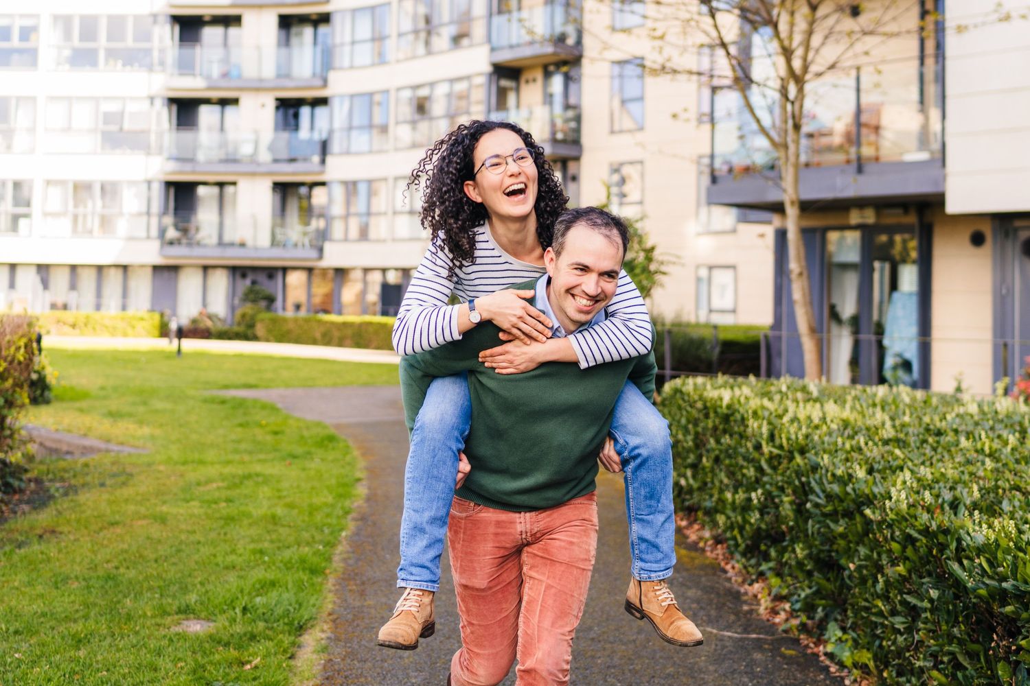 Parent and child posing and laughing together outside their apartment complex on a sunny day. PHOTOGRAPHER Dublin ireland