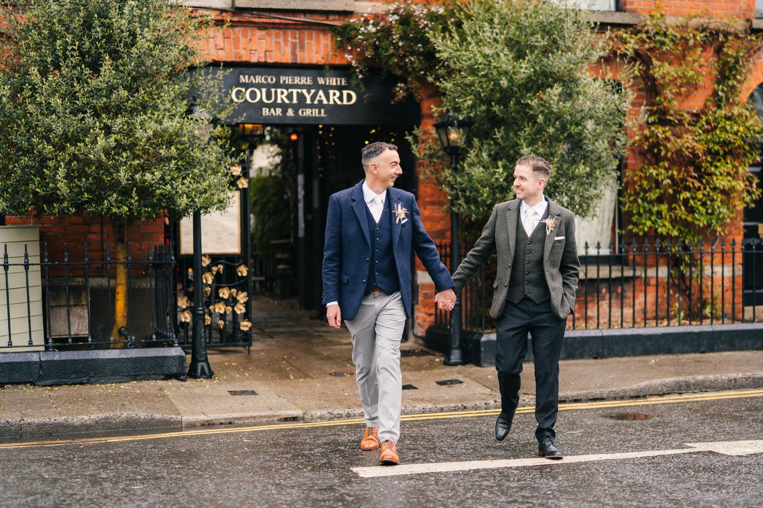 Two people walk together in business attire on a sidewalk outside the Courtyard entrance.