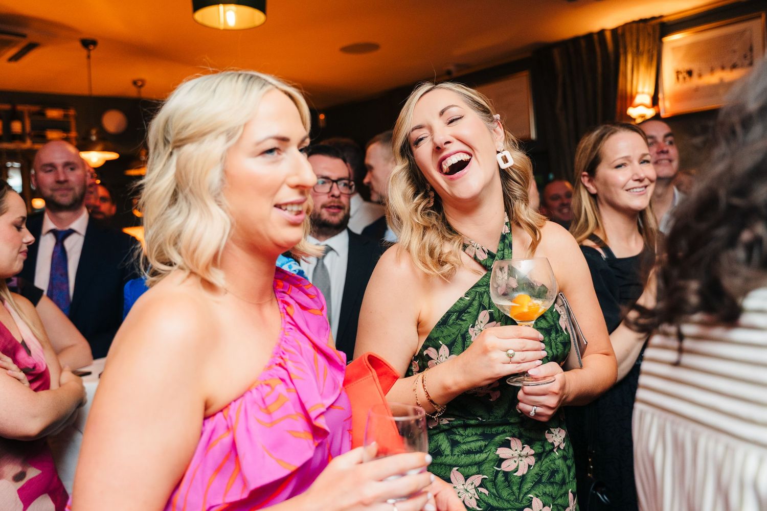 Party guests in formal attire laughing and enjoying cocktails at evening event. Marco Pierre Dublin Wedding Photographer