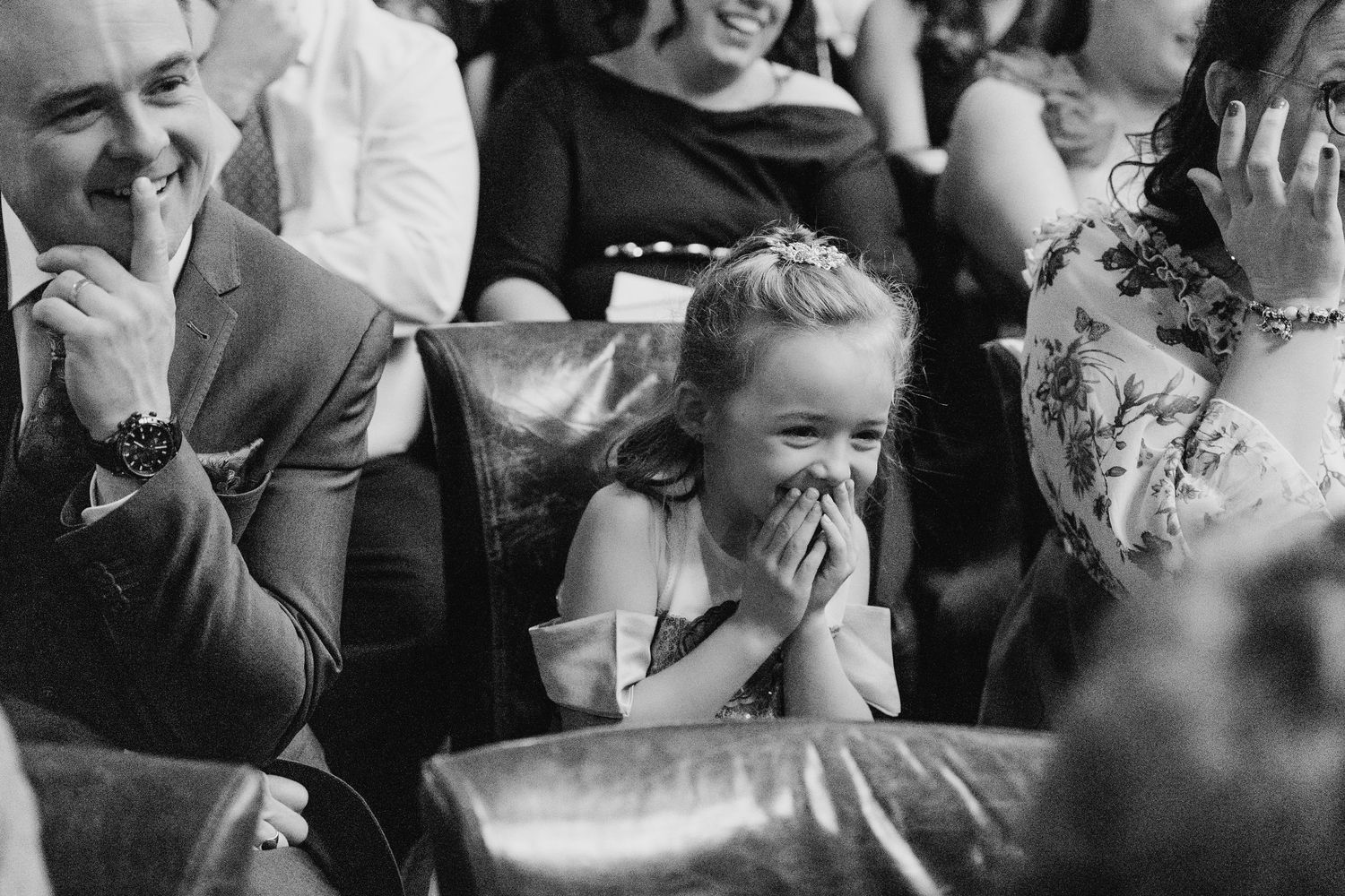 A black and white photo captures a young child giggling during a wedding celebration. Marco Pierre Dublin Wedding Photographer