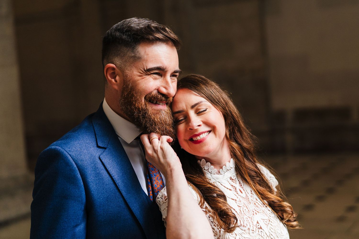 A happy couple share a joyful moment together, with one wearing a blue suit and the other in white lace. Wedding PHOTOGRAPHER Dublin