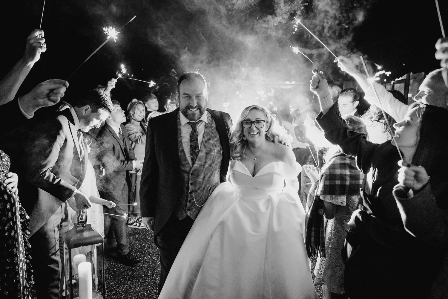 Black and white wedding sparkler exit photo sequence showing newlyweds walking through glowing sparklers held by guests.
