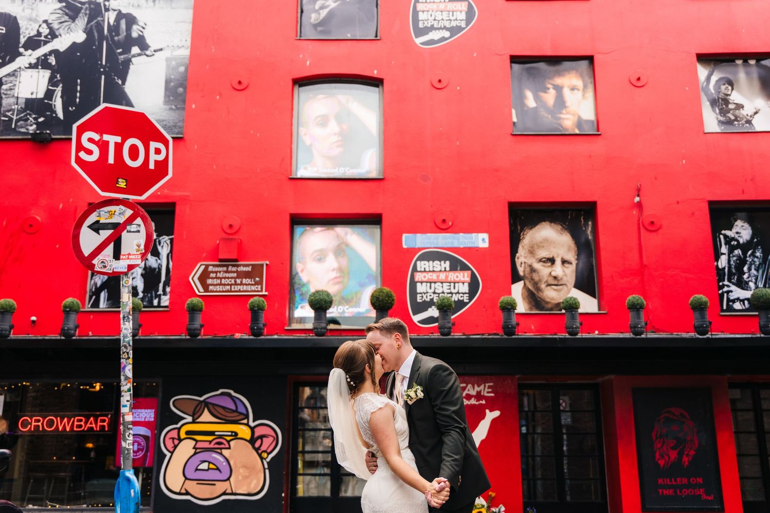 A vibrant red exterior storefront with a Stop sign and various photos displayed on the wall creates an eye-catching facade. Wedding PHOTOGRA