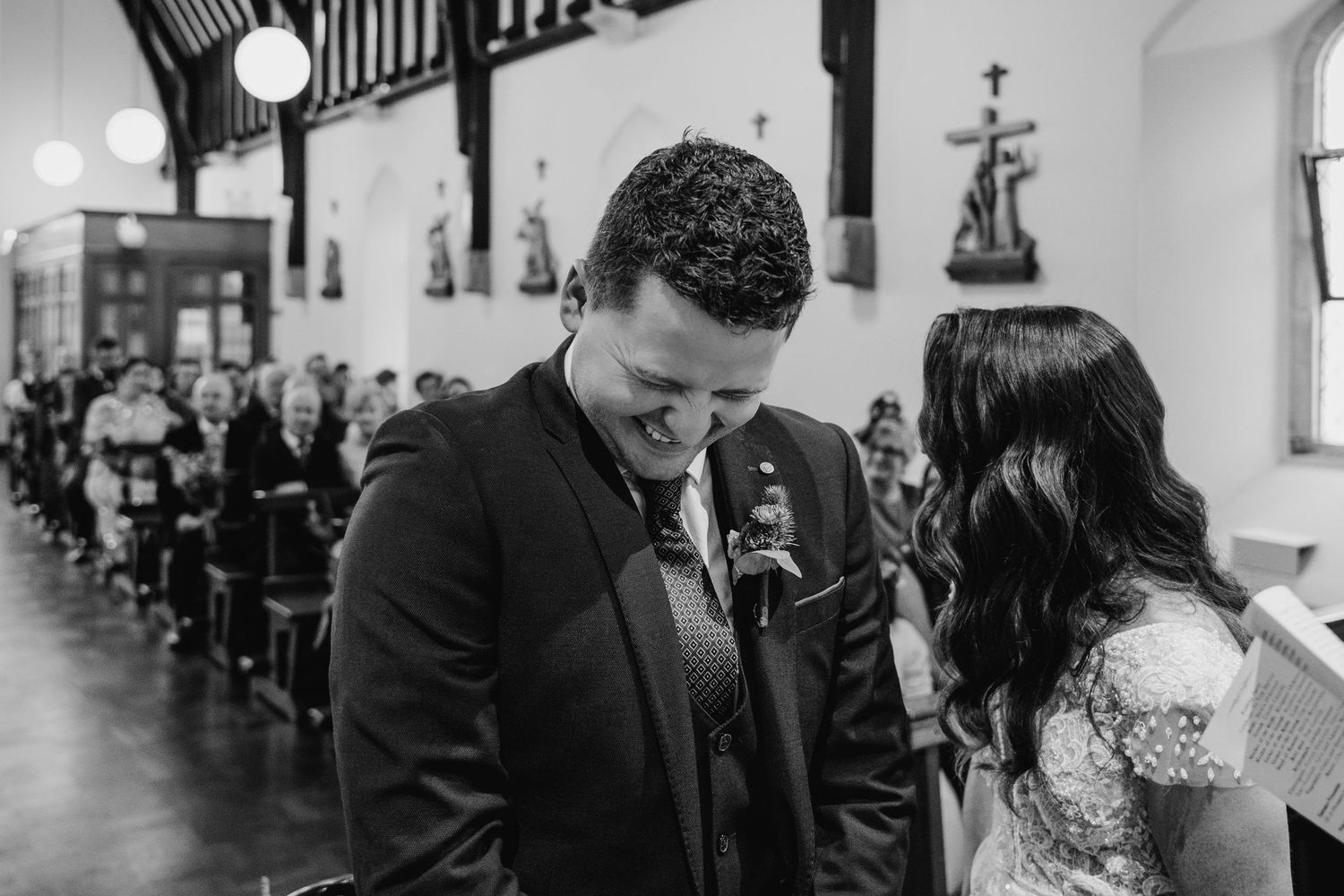 Black and white photo of wedding ceremony inside historic church with architectural details.