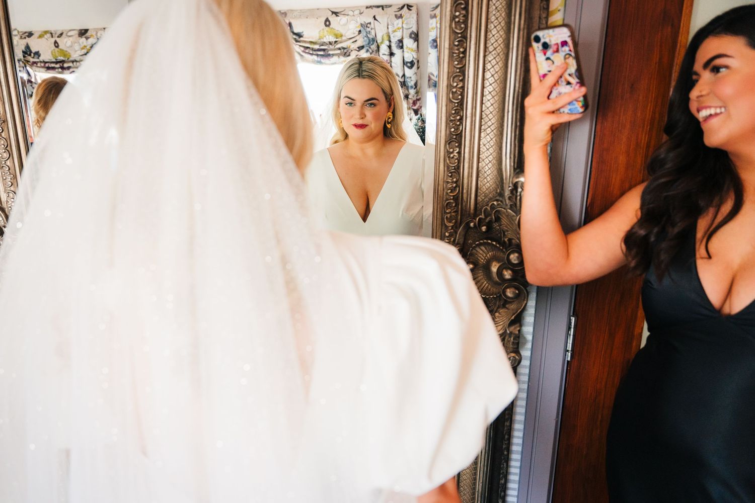 Wedding party members prepare in an ornate room with a large mirror and flowing white wedding dress. City Hall Dublin Photographer