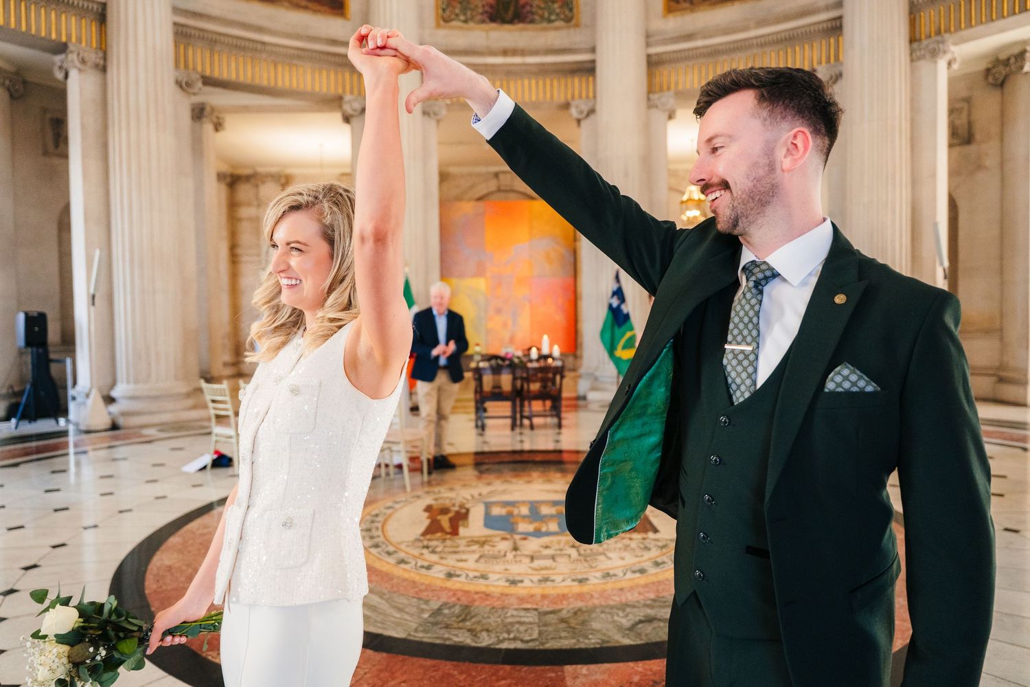 A couple shares a celebratory dance moment in an elegant room with classical columns. City Hall Dublin wedding photogrAPher