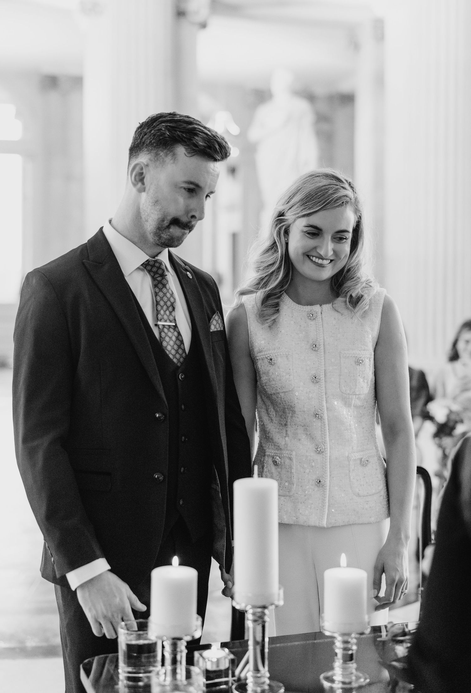 A couple performs a unity candle ceremony during their wedding with white candles arranged on an elegant table. City Hall Dublin wedding pho