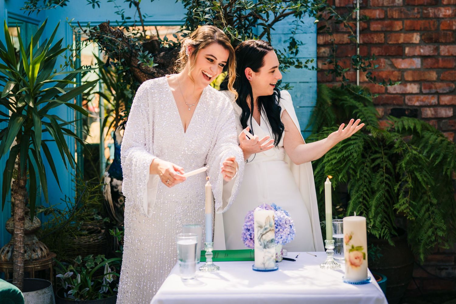 Wedding guests chat at an outdoor table near lush greenery and brick walls. House Dublin Wedding Photographer