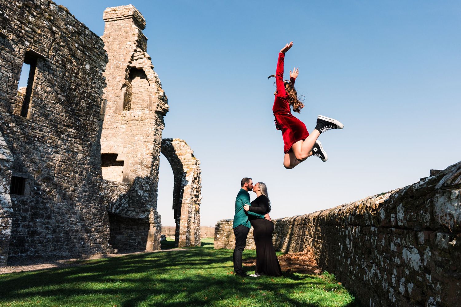 A person in red performs an impressive aerial flip at ancient castle ruins while others watch. Family PHOTOGRAPHER Dublin