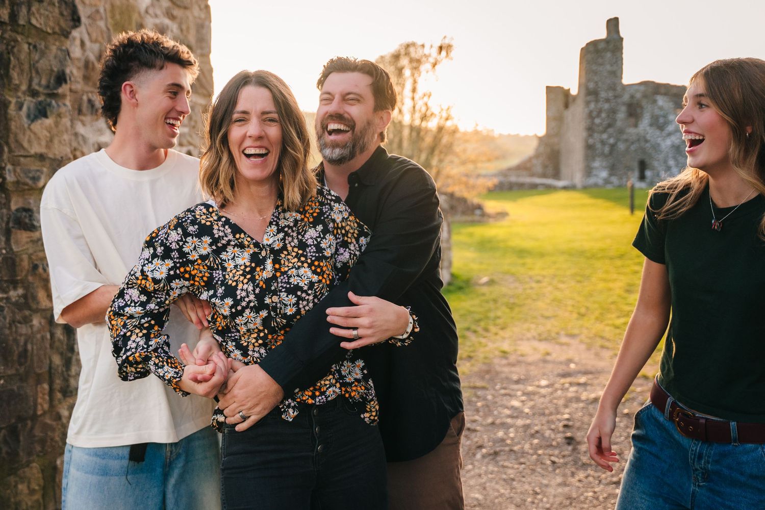 Group laughing together outside historic stone castle ruins during golden hour. Photographer Ireland dublin