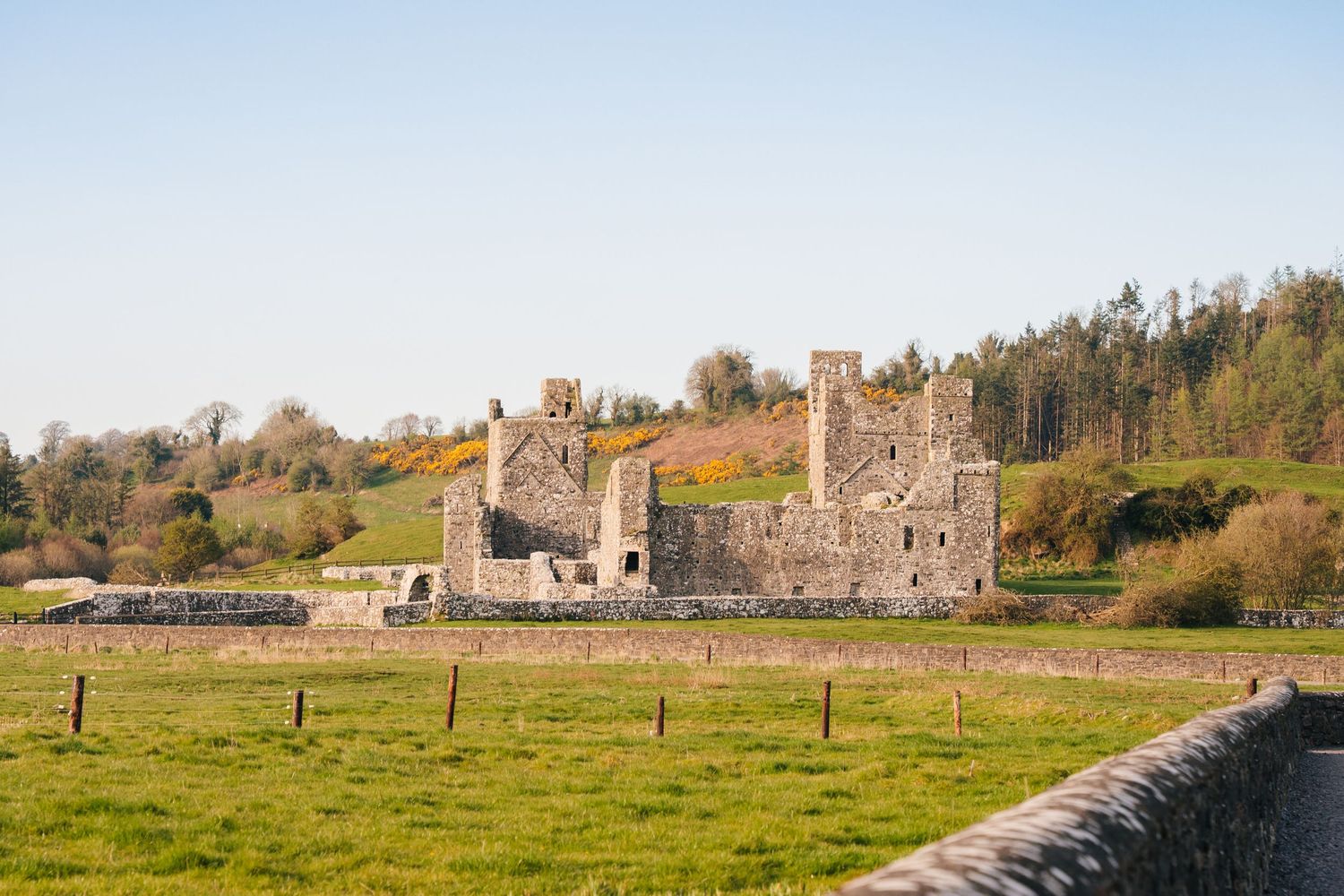Ancient stone castle ruins stand in green countryside under blue sky. Photographer Ireland dublin