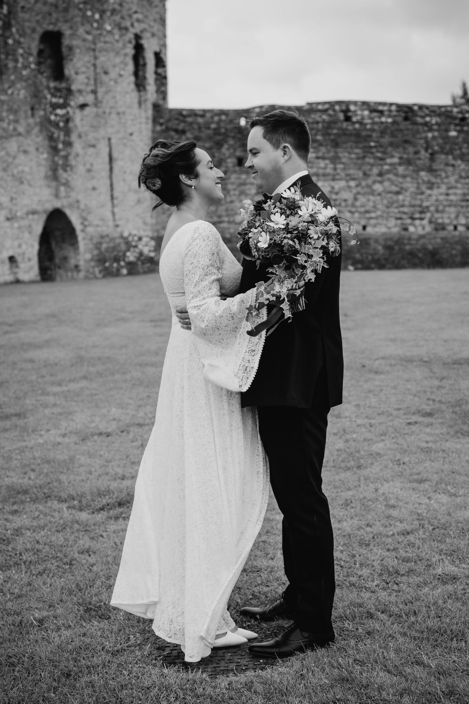 Black and white portrait of newlyweds embracing by ancient castle ruins. Wedding Photography Trim Castle Ireland