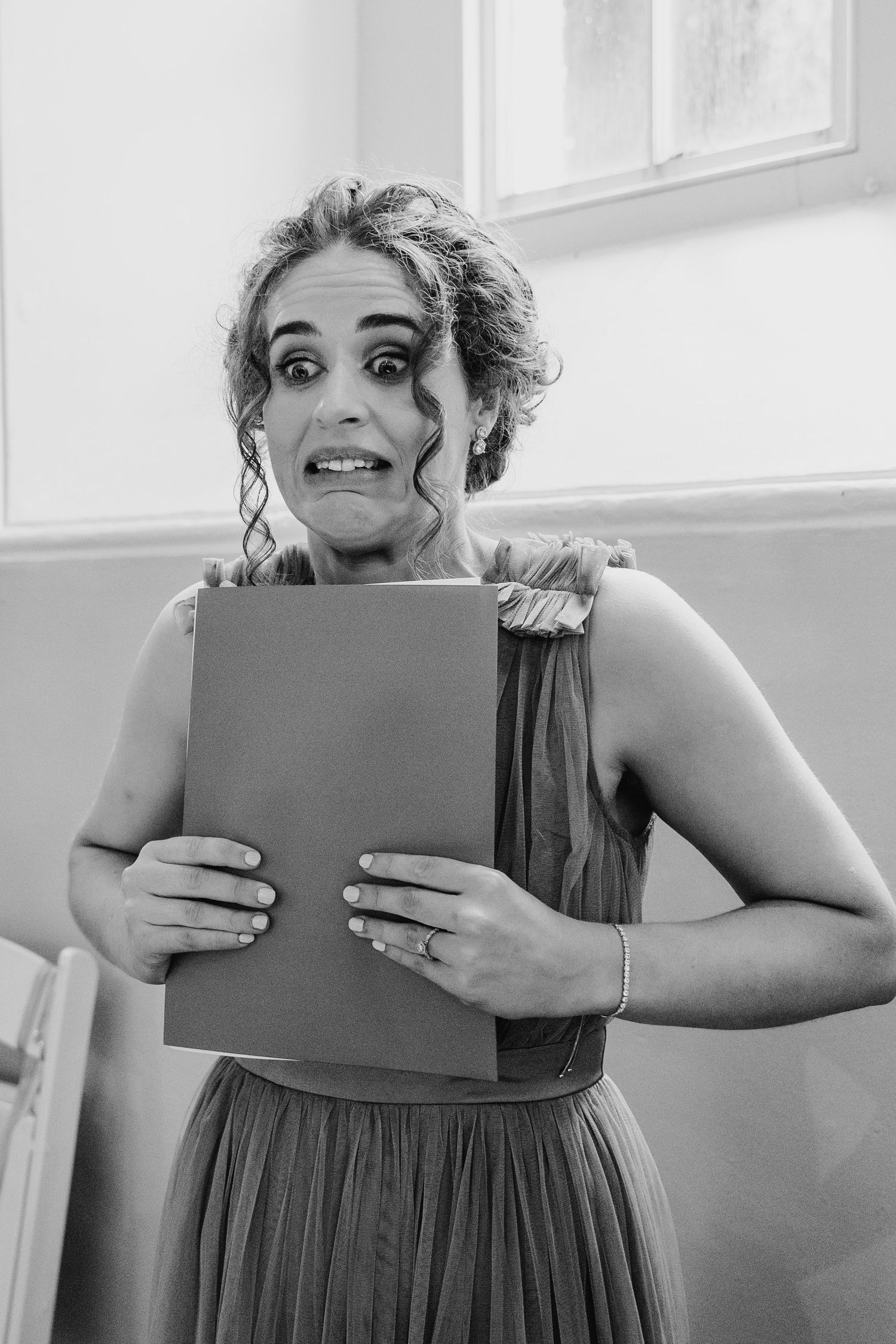 Millhouse slane wedding photographer dublin Black and white portrait of a bridesmaid holding a folder with excited expression.