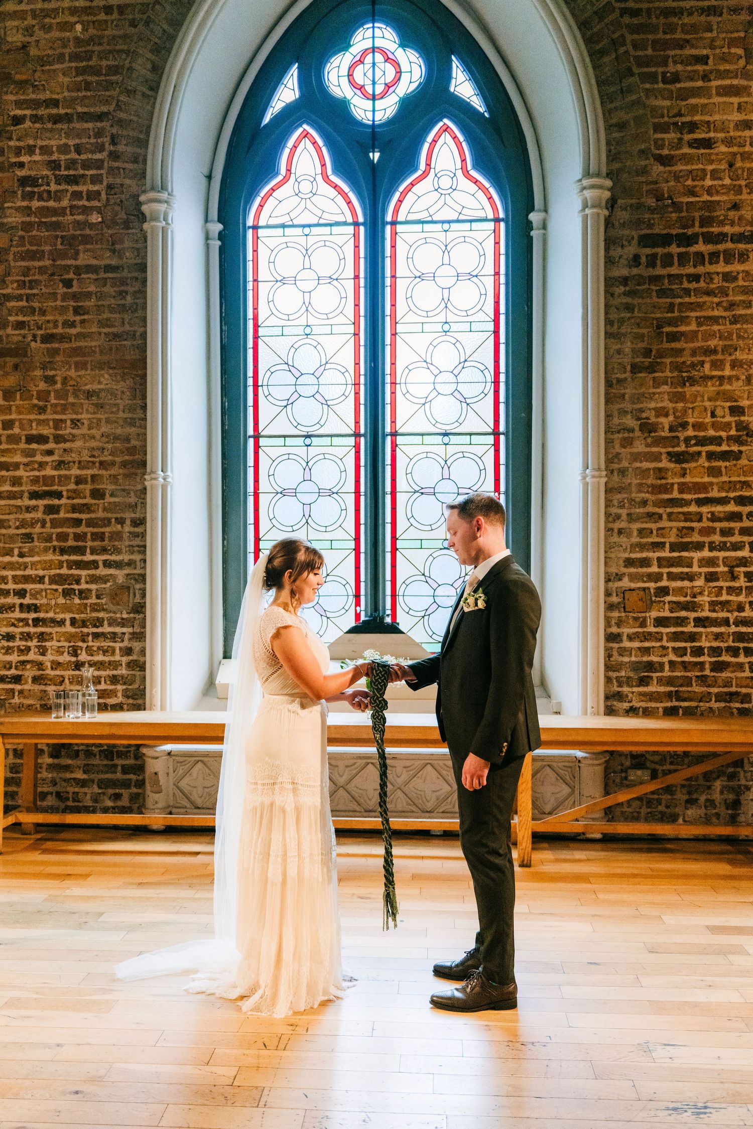 First look between wedding couple in a beautiful church with stained glass windows and exposed brick walls. PHOTOGRAPHER Dublin Ireland Wedd