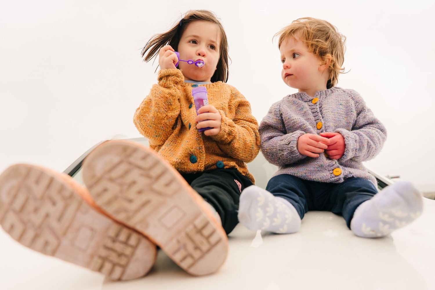 Two toddlers sitting together in matching outfits while drinking from sippy cups. family photographer dublin