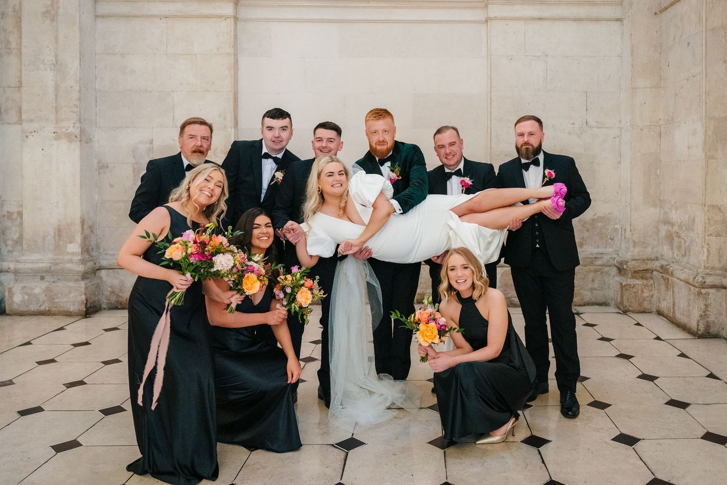 Wedding party in black and white attire poses together on checkered floor. Wedding photographer dublin