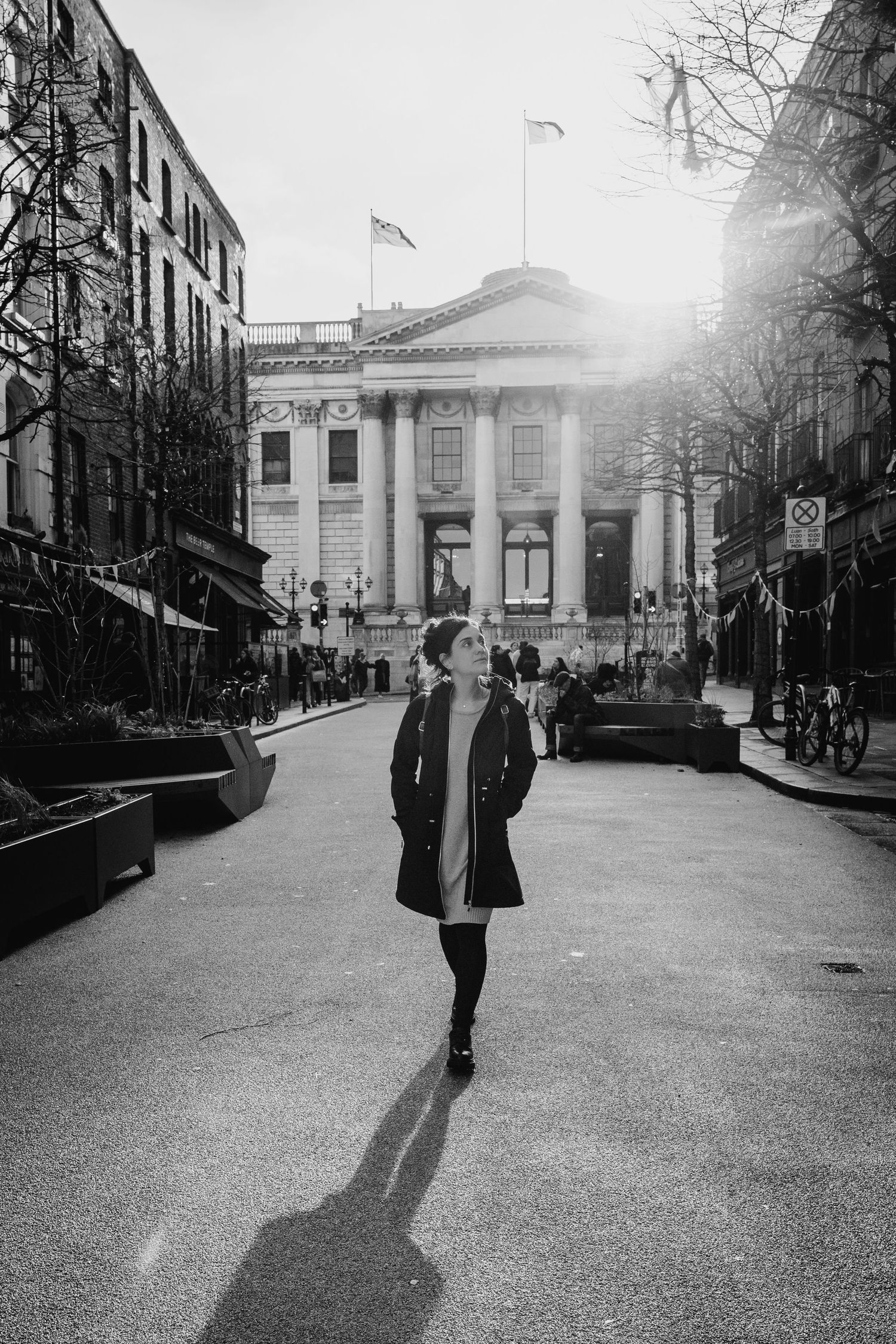 Black and white photo series showing a person walking down an urban street with long shadows cast on the pavement. professional headshots du