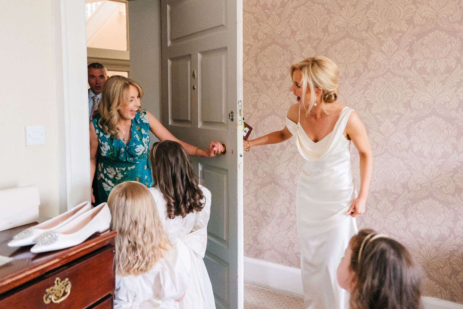 A bride in a white dress shares a joyful moment with loved ones while getting ready in an elegant room. wedding photographer dublin pricing