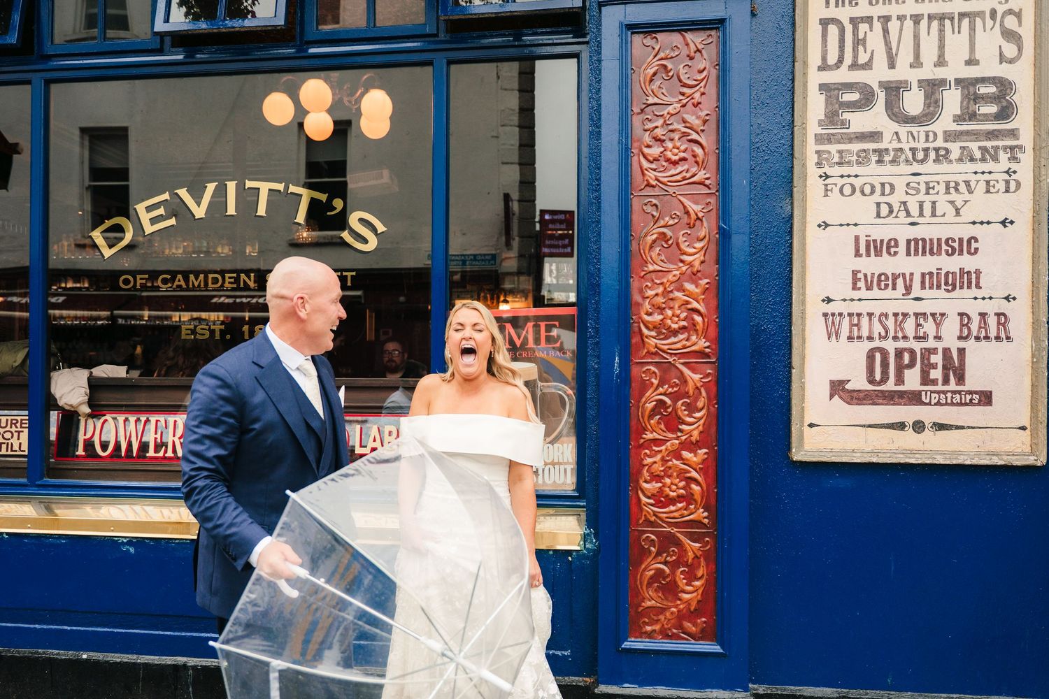 Wedding couple posing outside Devitt's Pub with its classic blue storefront and signage. The Dean Dublin Wedding Photographer