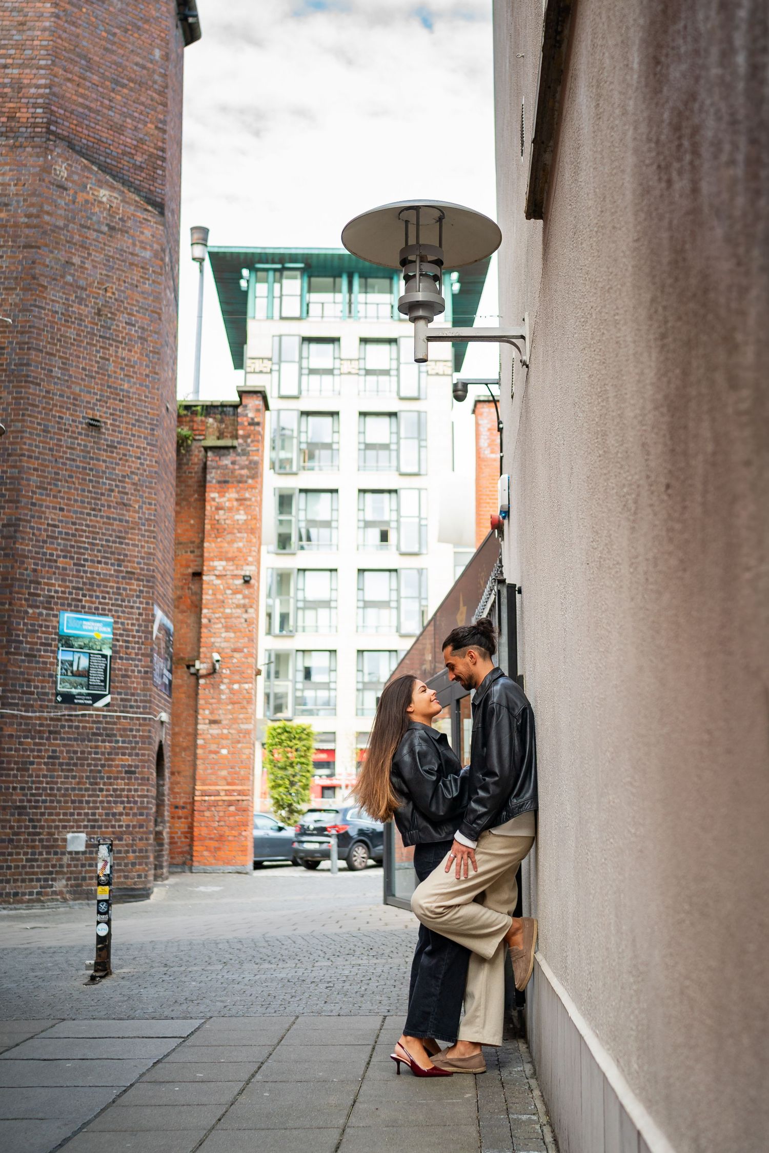 A couple embraces in an intimate moment against a brick wall in an urban archway setting. Couple's Photoshoot PHOTOGRAPHER Dublin