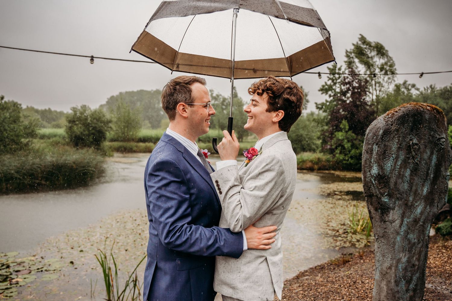 Wedding couple shares intimate moments under umbrellas in an outdoor setting near a lake. Wedding photographer Dublin