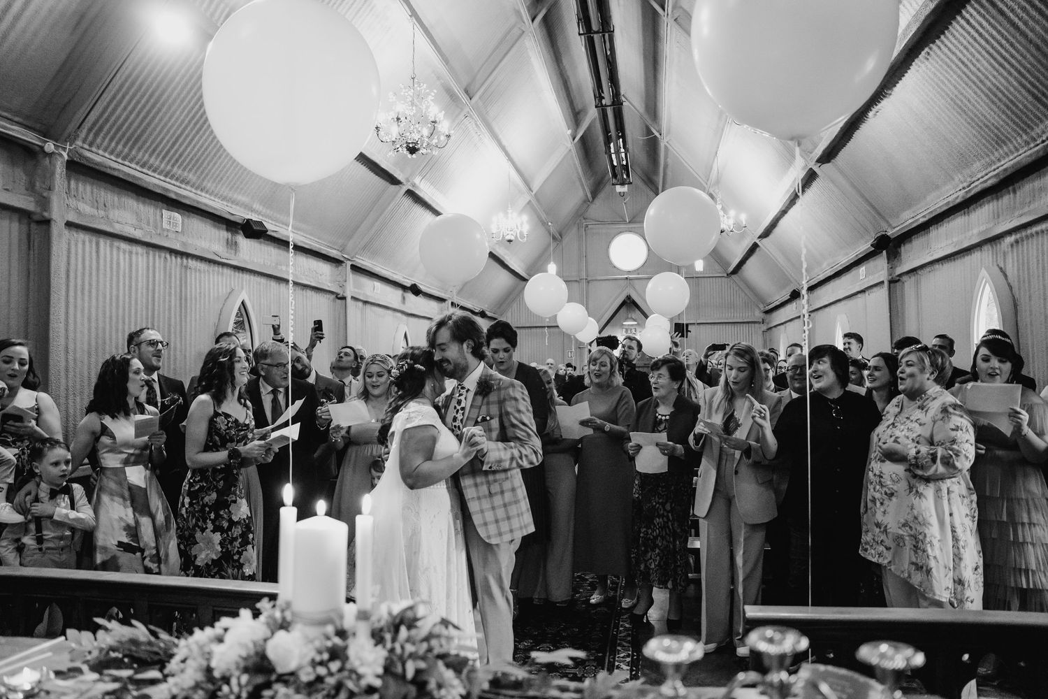 Large reception hall decorated with hanging lanterns and filled with celebrating wedding guests. Wedding photographer Dublin
