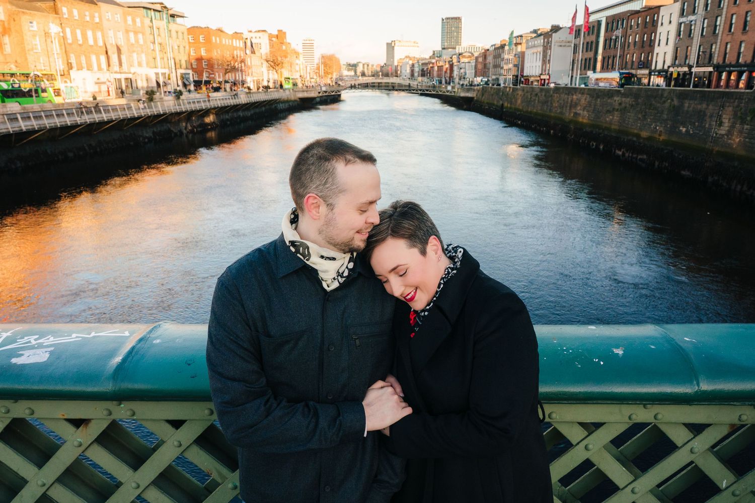 A couple shares an intimate moment on a bridge over Dublin's River Liffey at sunset. family photographer Dublin ireland