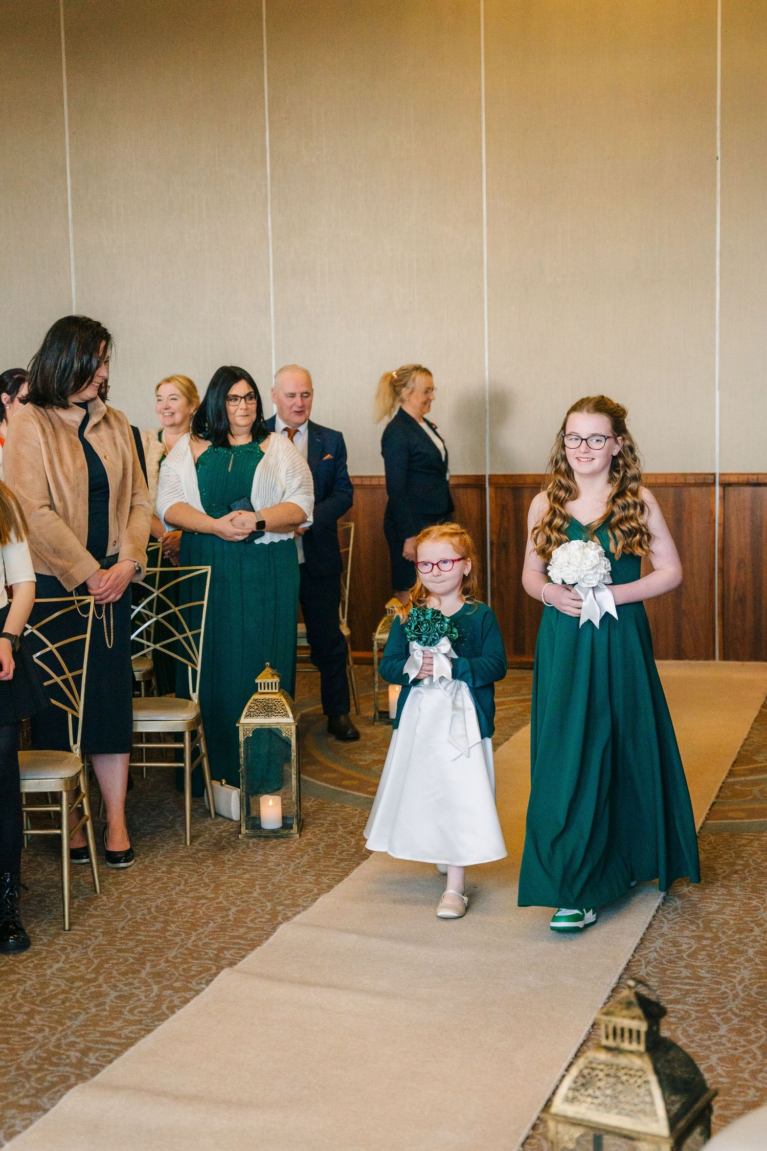 Wedding guests in emerald green dresses and formal attire gather in an elegant reception hall.  Wedding PHOTOGRAPHER Trim Castle