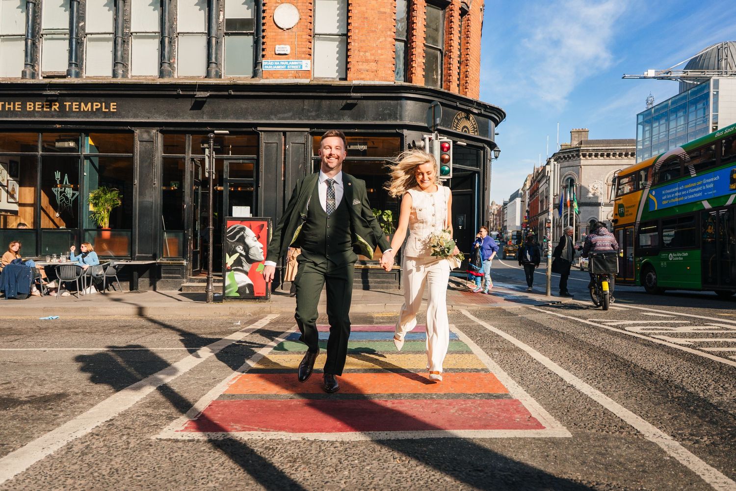 Couple walks across urban street intersection in Dublin with historic buildings in background. City Hall Dublin wedding photogrAPher