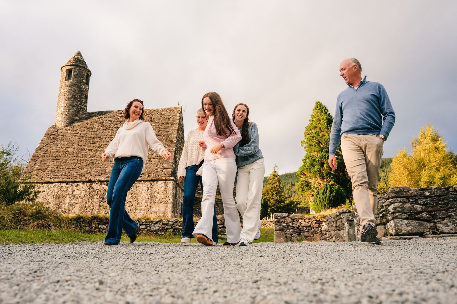 Family photographer Ireland Dublin People posing together on a rocky beach with mountains and castle ruins in the background.