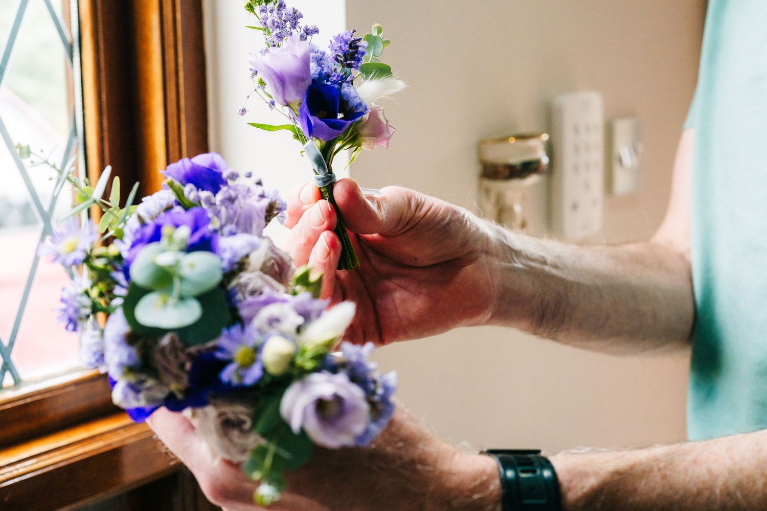 Hands arranging delicate purple and white flowers in a soft natural light by a window. Millhouse slane wedding photographer dublin