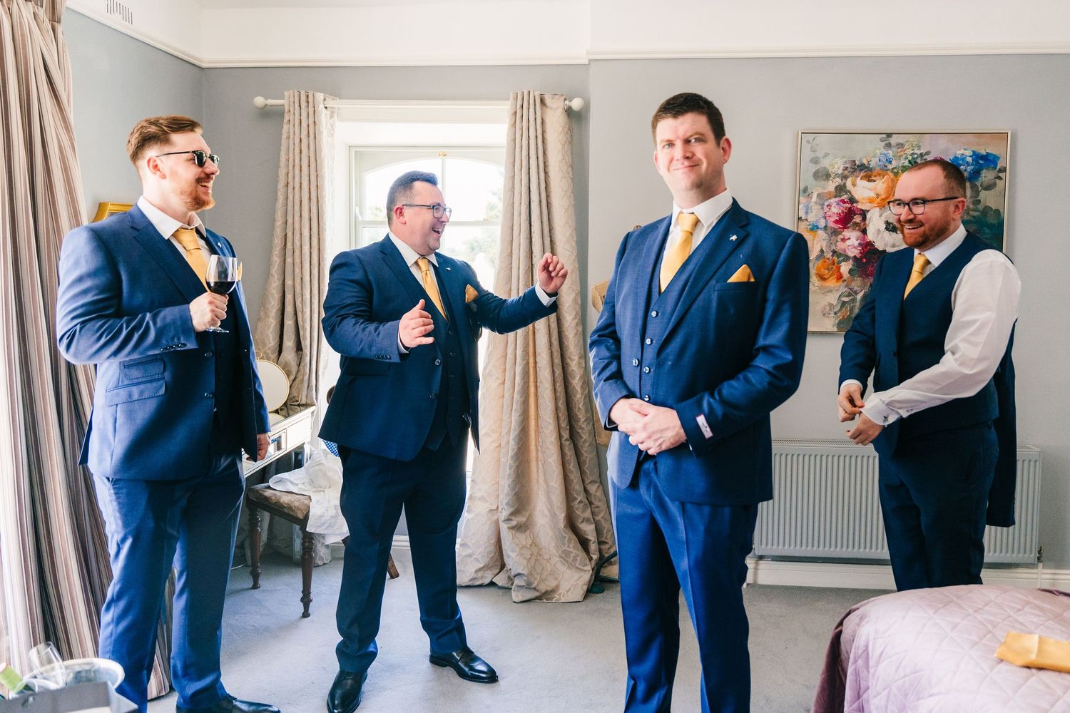 Poulaphouca Wedding photographer wicklow  Groomsmen in matching navy blue suits share a lighthearted moment while getting ready.