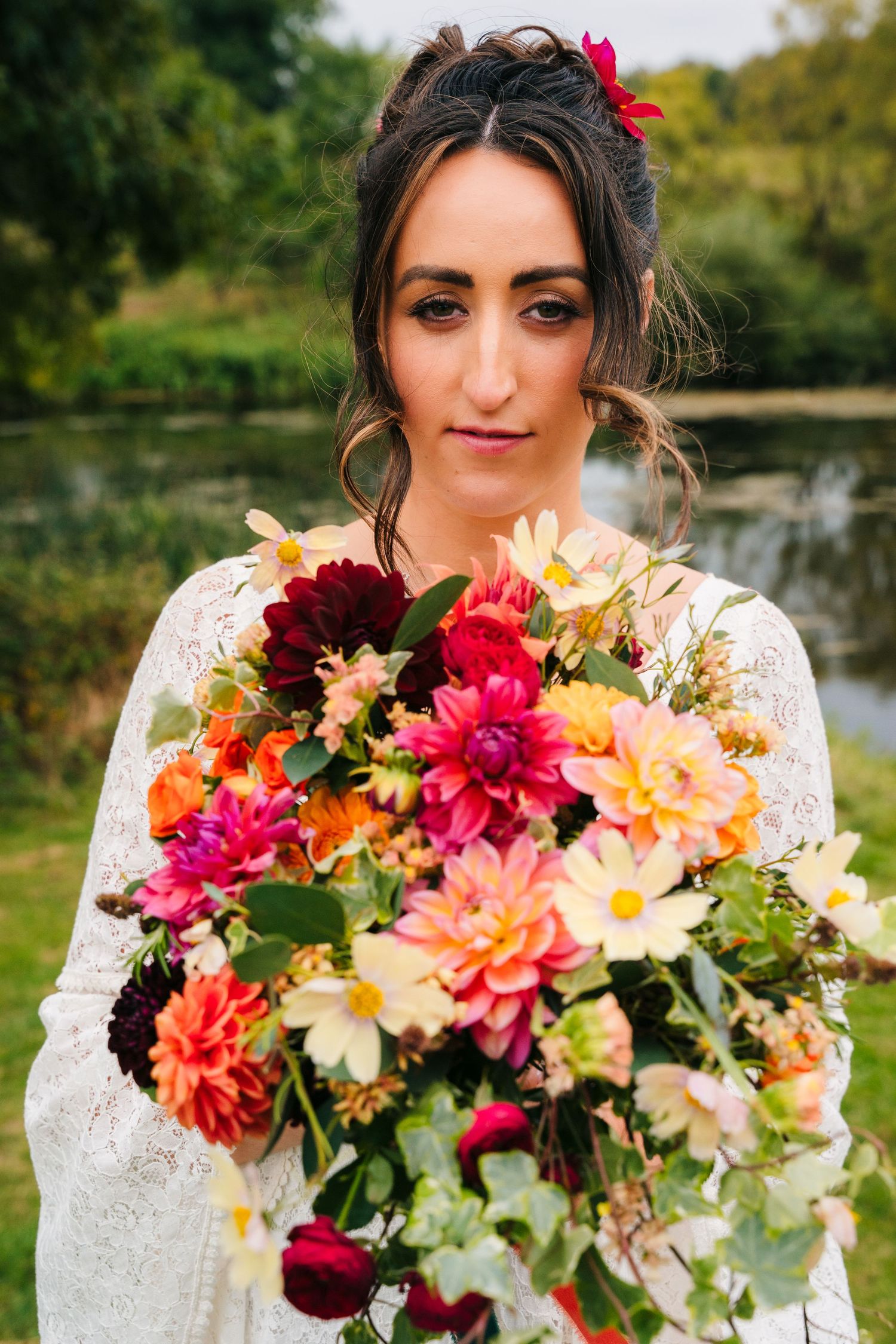 A series of wedding photos showcasing a stunning bridal bouquet with vibrant dahlias, lilies and autumnal florals in orange and pink tones.W